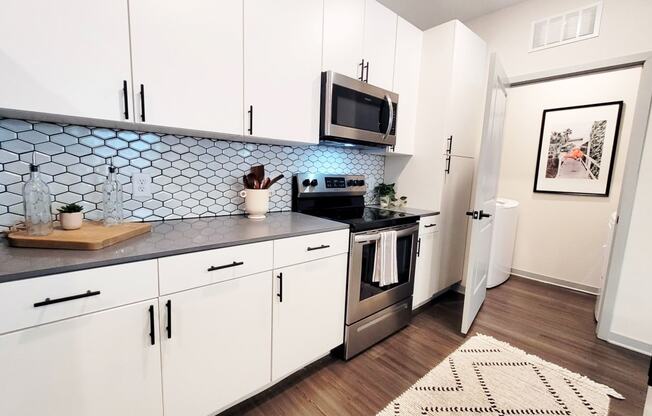 a kitchen with white cabinets and a black and white rug