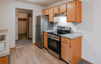 an empty kitchen with wooden cabinets and stainless steel appliances