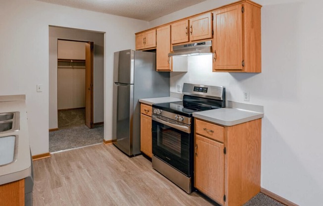 an empty kitchen with wooden cabinets and stainless steel appliances