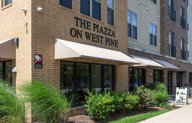 The Plazza on West Pine is a multi-story building with a beige facade and a white awning.