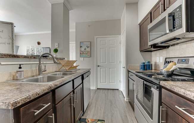 A kitchen with a sink, stove, and microwave.