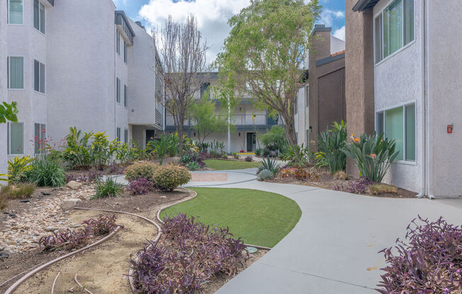 an exterior view of an apartment building with a sidewalk and grass at City View Apartments at Warner Center, California
