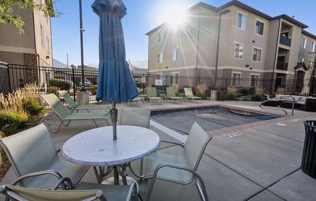 our apartments have a pool and a patio with chairs and an umbrella