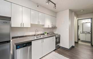 A modern kitchen with white cabinets and stainless steel appliances.