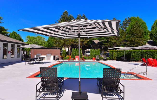 Apartment Kirkland WA - Woodlake - Pool Area with Lounge Chairs, Tables, and Striped Umbrellas