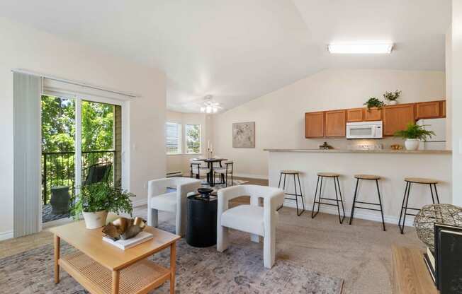 a living room with a island bar and a kitchen with stools