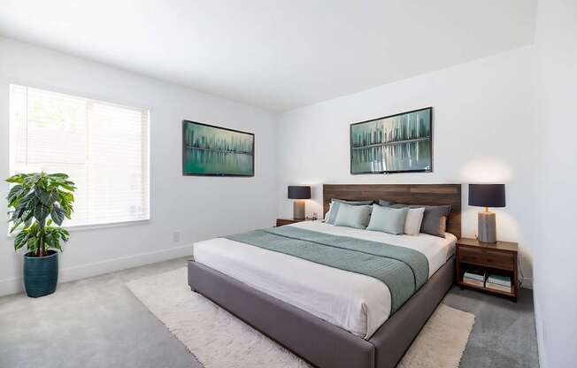 A bedroom with a large bed and two pictures on the wall.
