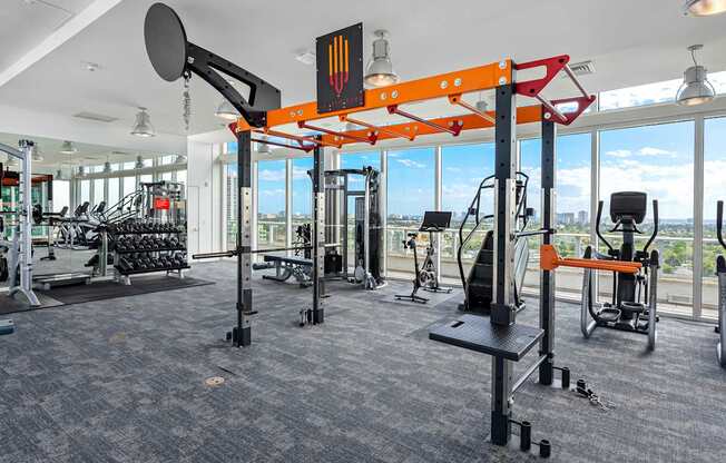 A gym with a variety of equipment including a squat rack, bench press, and a rowing machine.