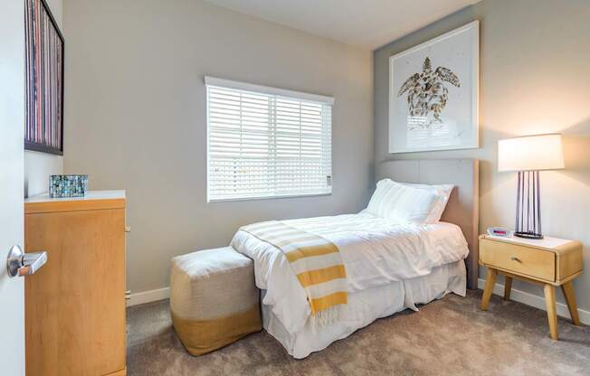 A bedroom with a bed, nightstand, and lamp.