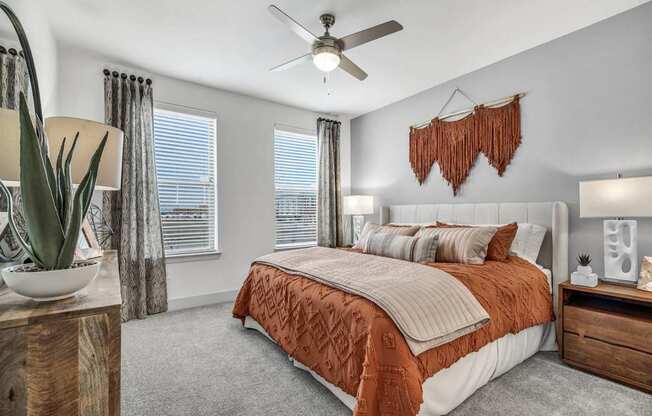 A bedroom with a bed, a ceiling fan, and a wooden nightstand.