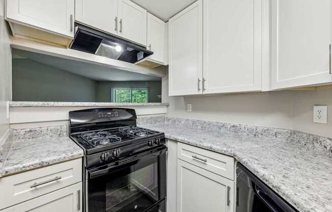 A kitchen with a black stove top oven and white cabinets at Gwinnett Square Apartments in Duluth, GA