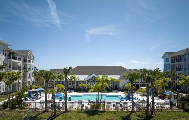 an aerial view of a swimming pool with palm trees in front of an apartment complex