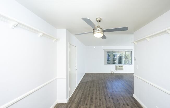 a living room with white walls and a ceiling fan