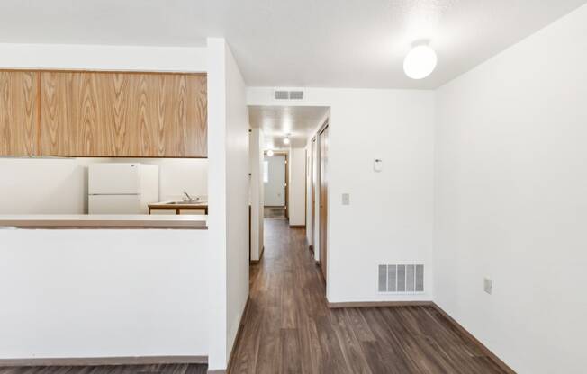 a renovated living room and kitchen with white walls and wood floors