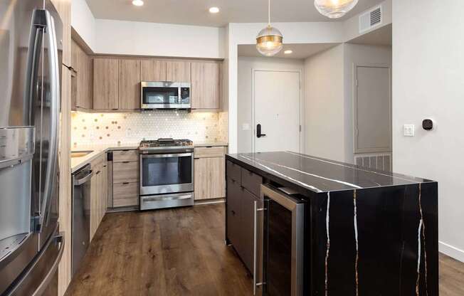 A modern kitchen with a black marble island and stainless steel appliances. at Elements Apartments*, California, 92612