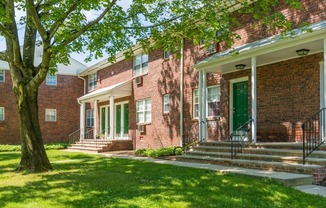 a brick building with green doors and a tree in front of it at Nottingham Manor Apartments, New Jersey