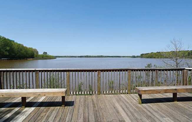 A wooden deck overlooks a body of water with benches on either side.