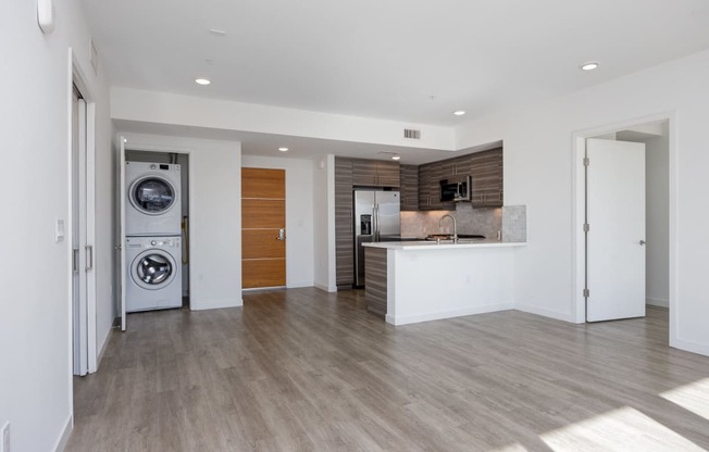 a living room with a washer and dryer and a kitchen