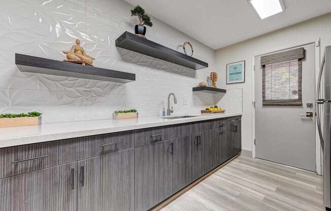 A kitchen with a white counter top and grey cabinets.