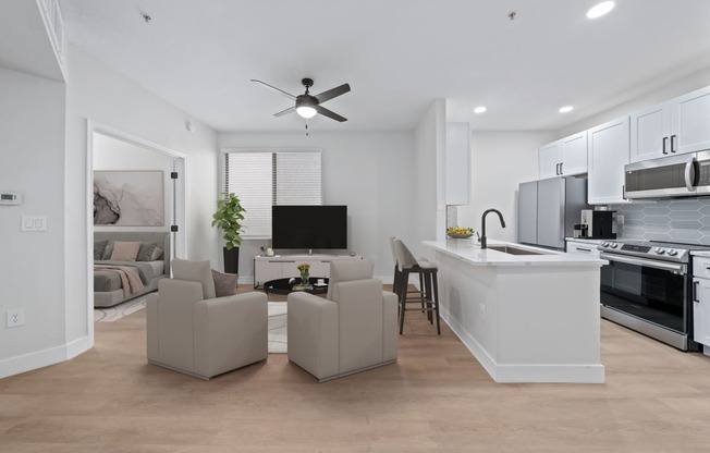 a living room with couches and a kitchen and a ceiling fan