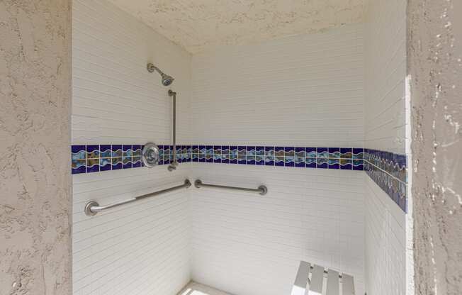 a walk in shower with white walls and blue tile