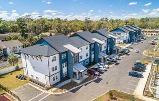 an aerial view of a row of multifamily buildings with a parking lot and trees in the