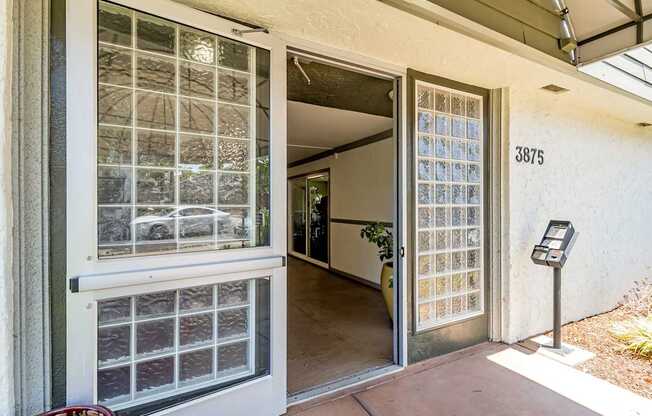 A glass door with a metal frame is open to a hallway.