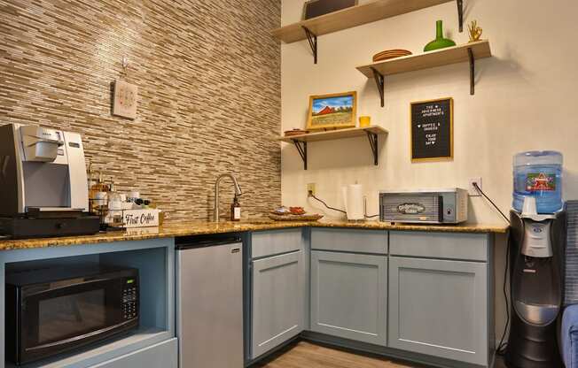 A resident lounge with a mini fridge, water cooler, microwave, and coffee machine at The Inverness Apartments in Houston, TX