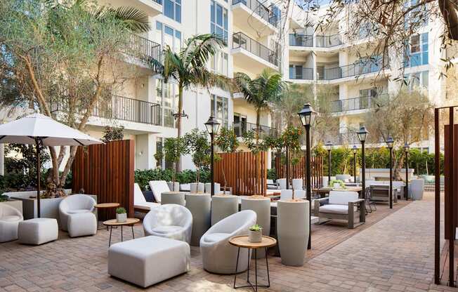 Dog-Friendly Apartments in Hollywood, CA - The Fifty Five Fifty - Courtyard with Palm Trees, White Outdoor Furniture, and Tall Wooden Dividers