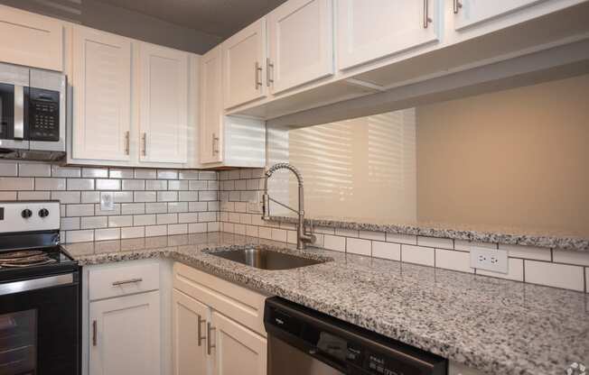 a kitchen with granite counter tops and white cabinets