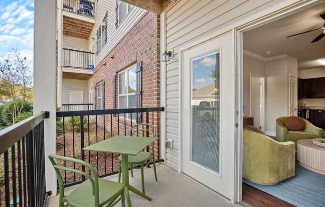 A balcony with a table and chairs overlooks a brick building.
