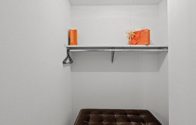 a brown bench in a white room with a shelf