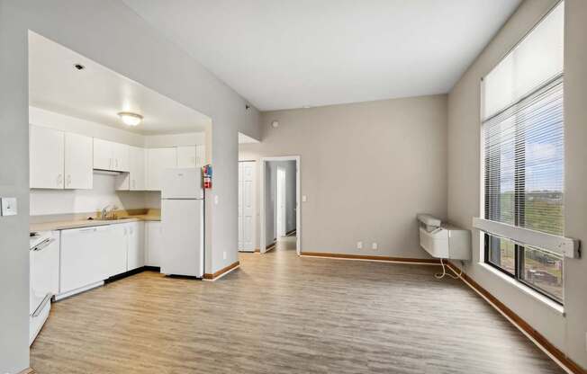 a spacious living room with a kitchen and a large window