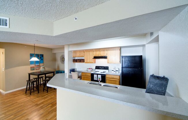 A kitchen with a white counter and a black fridge.