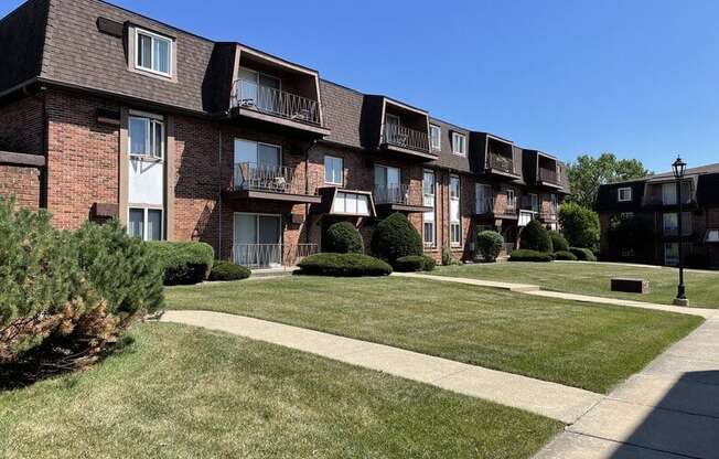 an apartment building with a grass yard and sidewalk