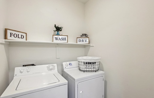 A laundry room with a washer and dryer and a laundry basket on top of the dryer.