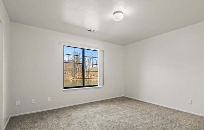 A spacious bedroom with a window and a carpeted floor at Tanglewood Apartments, Oak Creek, WI