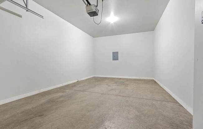 A room with a concrete floor and a white wall with a small square object on it.