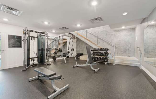 A gym with a variety of equipment including a bench, weights, and a squat rack.