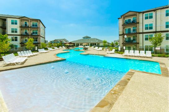 A large swimming pool in front of apartment buildings.