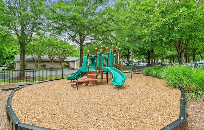 A playground with a green slide and a brown sandbox.