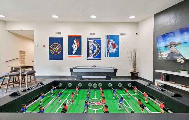 A foosball table is in the middle of a room with flags hanging on the wall.