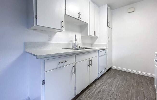 A kitchen with white cabinets and a grey counter top.