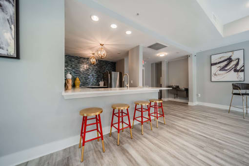 a bar with four red stools in a room with a kitchen