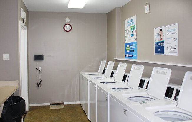 a laundry room with white washers and a clock on the wall