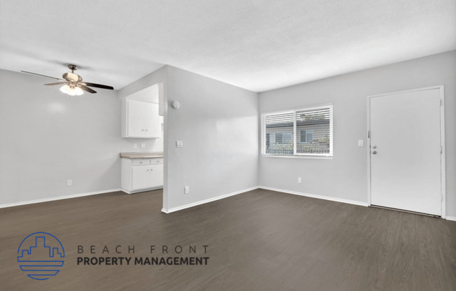 an empty living room with a ceiling fan and a bathroom