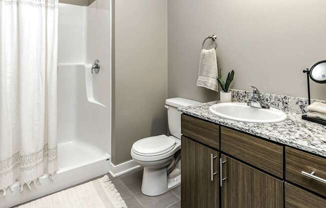 A white toilet sits in a bathroom next to a sink and a shower.