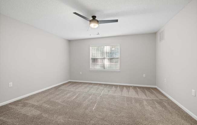 A room with a ceiling fan and carpeted floor.