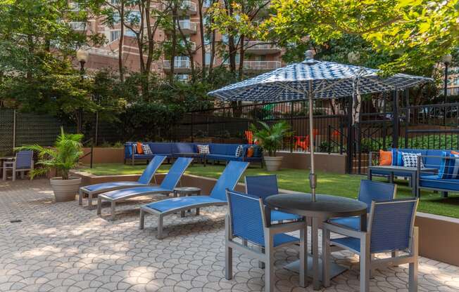 a patio with blue chairs and tables and an umbrella