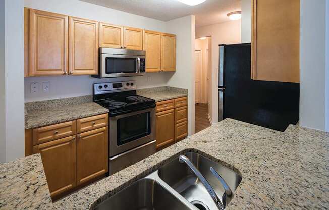 A kitchen with granite countertops and wooden cabinets.